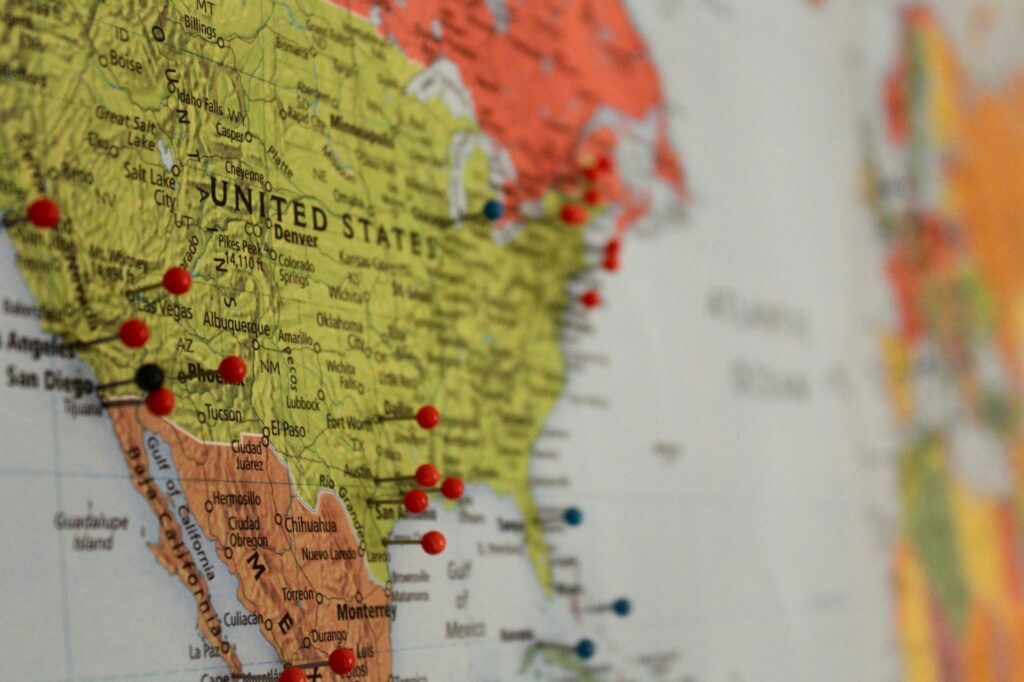 close up shot of the united states, on a world map, with pins in certain cities