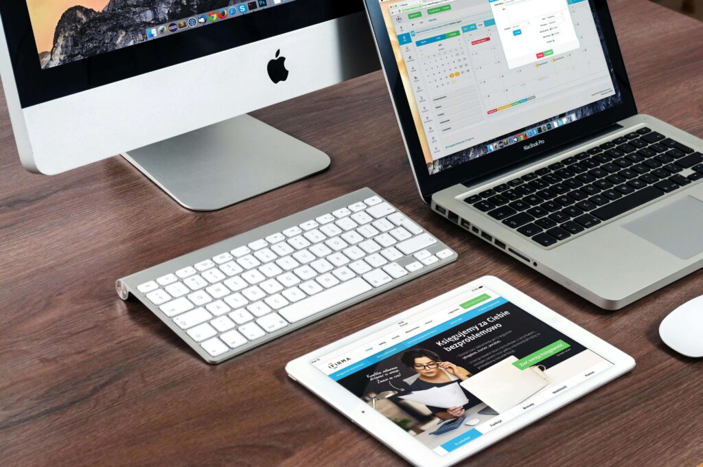 desk with tablet, laptop, and desktop on it